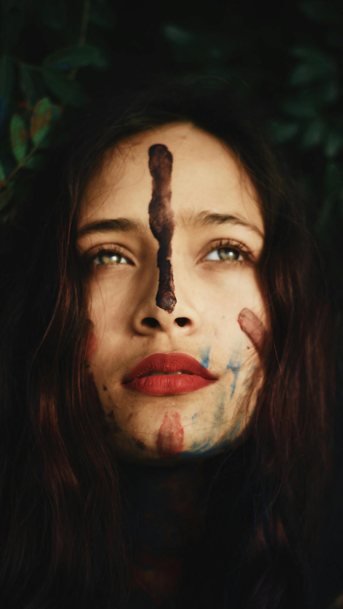 A captivating portrait of a woman with a painted face, set against a forest backdrop, evoking mystery.